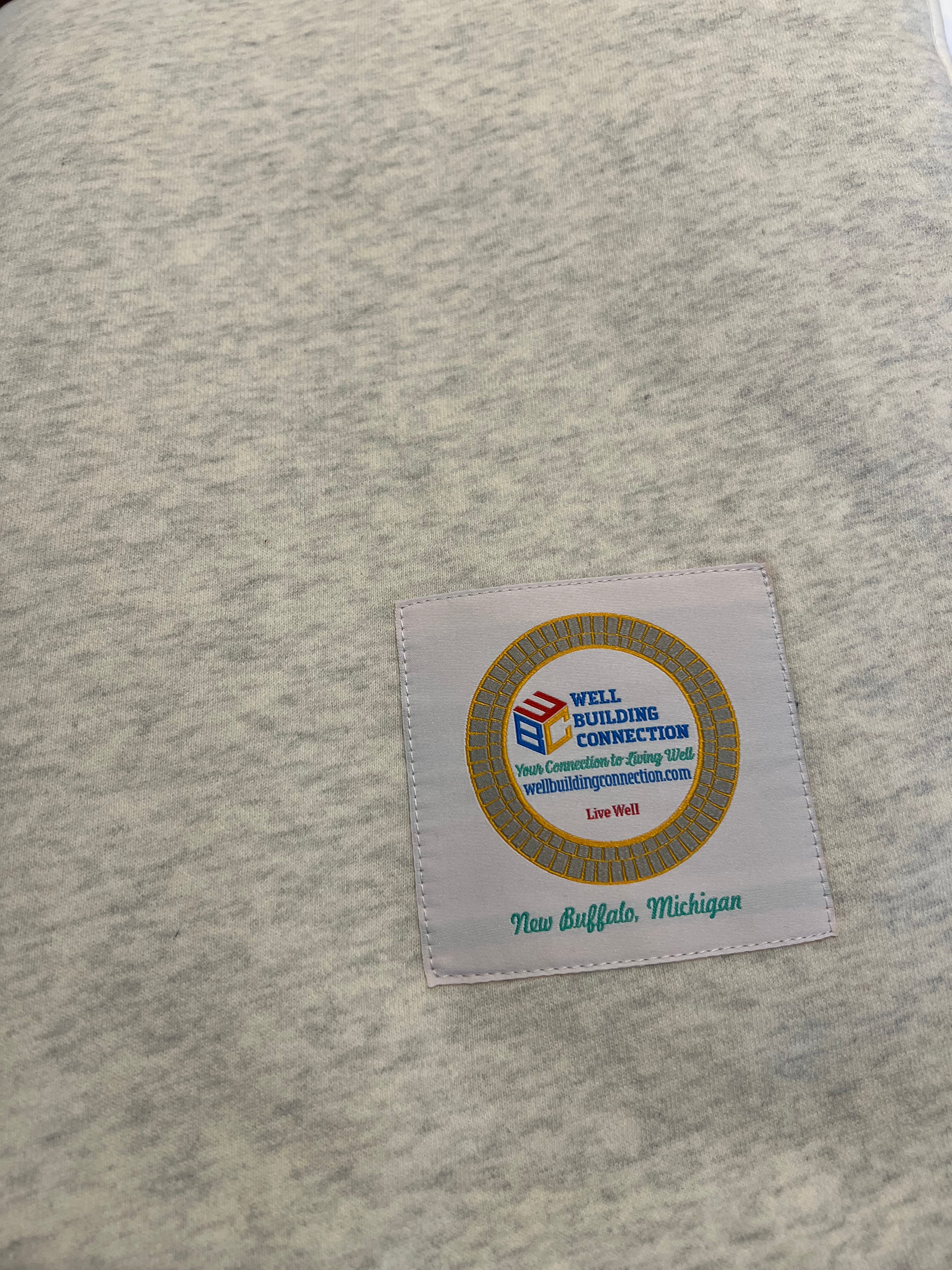 Well Building Connection Label with a logo and text on a textured fabric background of the grounding blanket. 