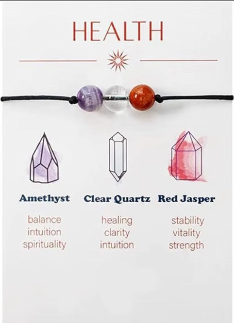 Crystal bracelet with beads labeled Amethyst, Clear Quartz, and Red Jasper on a white background. Mindfulness and Centering: These pieces often serve as tactile tools—reminders to breathe and refocus during stressful moments, helping you maintain emotional stability and intentionality throughout the day.