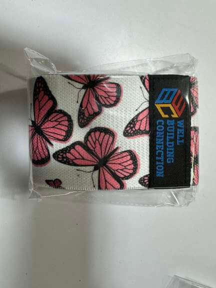 Fabric resistance band with pink butterfly design in packaging, featuring the Well Building Connection logo.